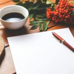 Empty paper sheet with pen and coffee next to red berries, ideal for design workspace concepts.