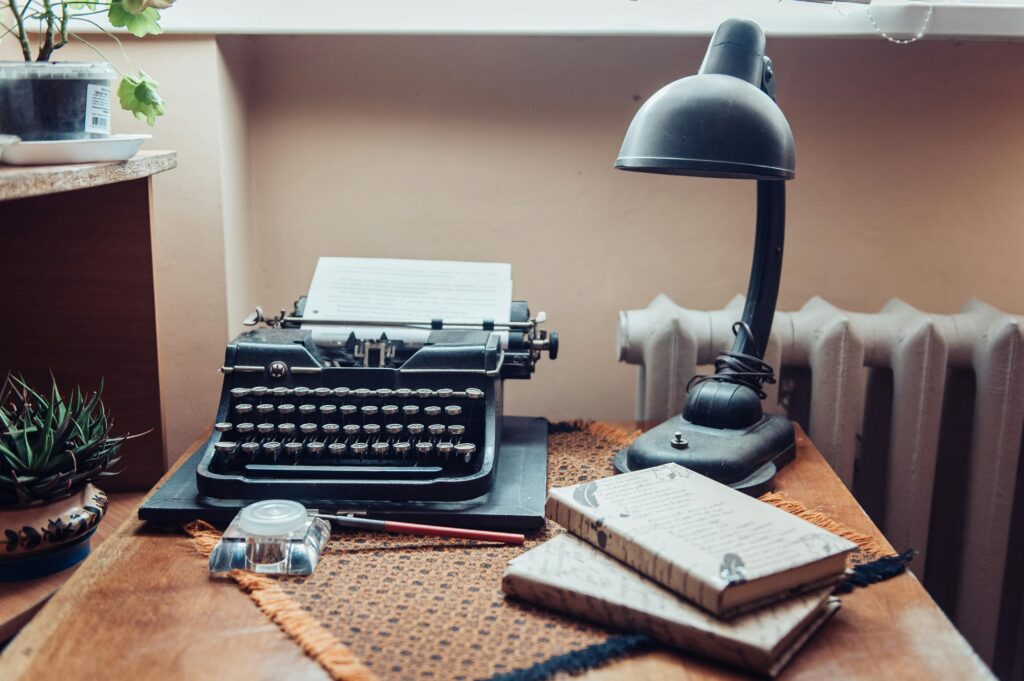 reconocimiento A cozy workspace featuring a vintage typewriter, desk lamp, and wooden desk setup.